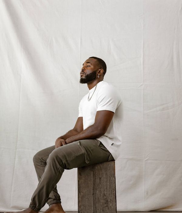 Man in a calm, meditative pose in a minimalist setting.